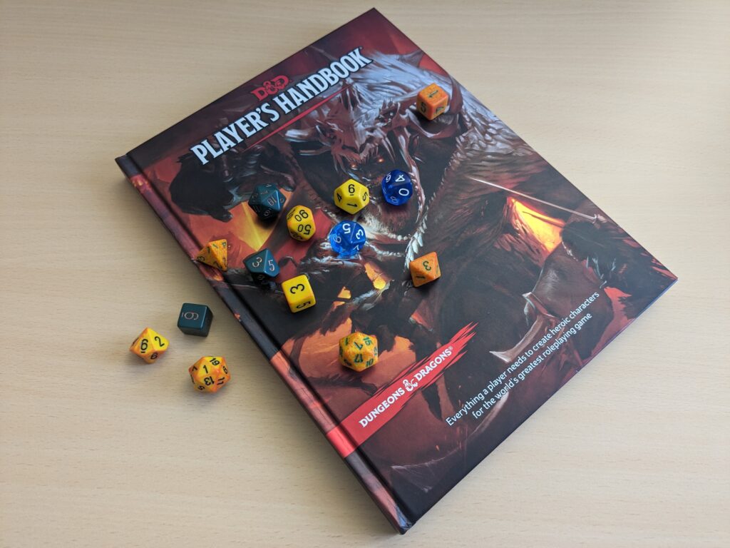 The Dungeons & Dragons "Player's Handbook" lies on a wooden surface, covered in a scatter of yellow, orange, green and blue polyhedral dice. Each d20 shows a "1".